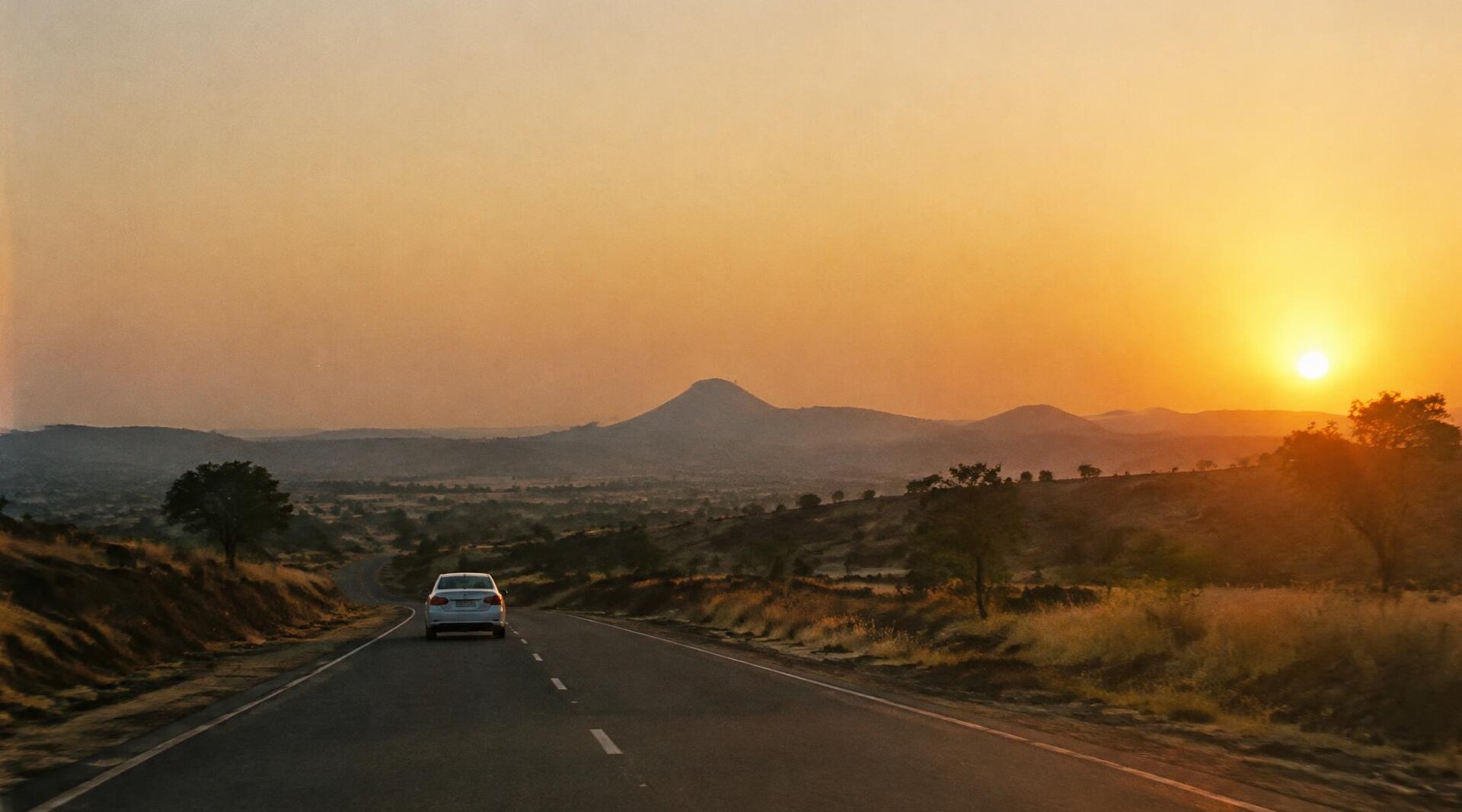 White taxi on an open highway at golden hour